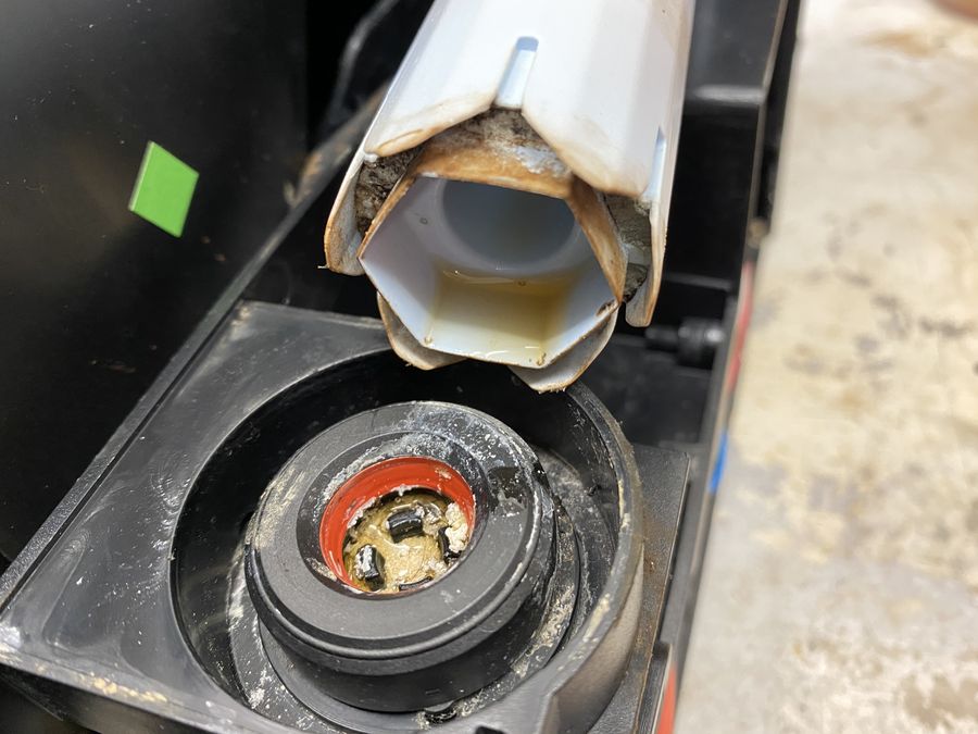 Blick von oben in einen geöffneten Kaffeevollautomaten mit verschmutzten Bauteilen